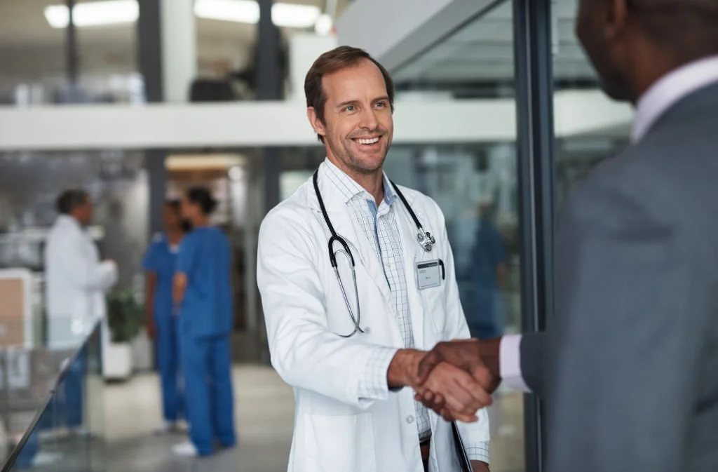 A manager shaking hands with a smiling doctor