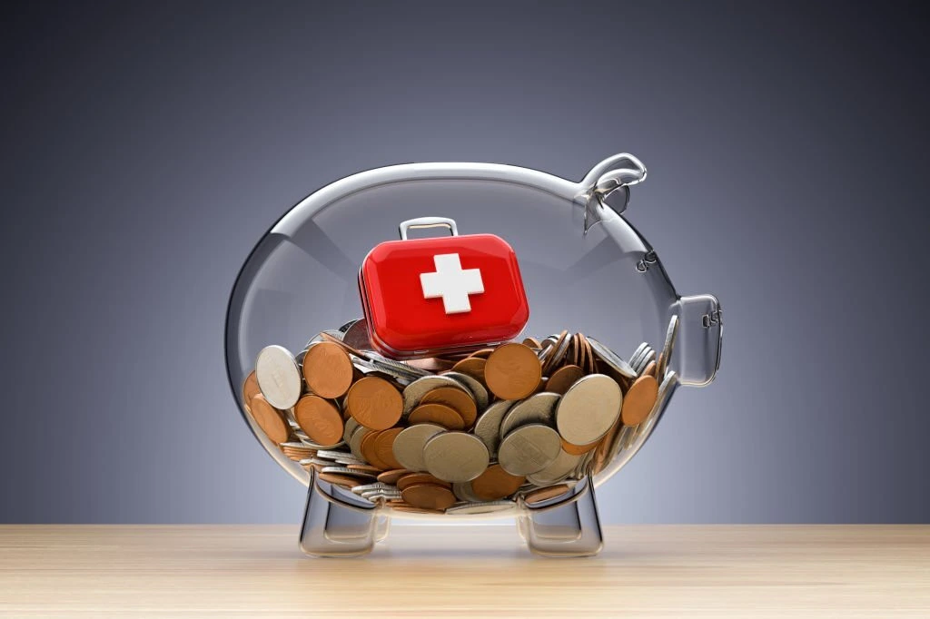 Coins and a medical sign inside a piggy bank